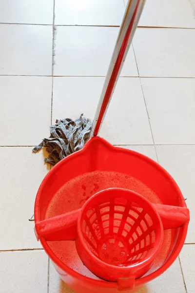 Balde vermelho com água e esfregando o chão — Fotografia de Stock