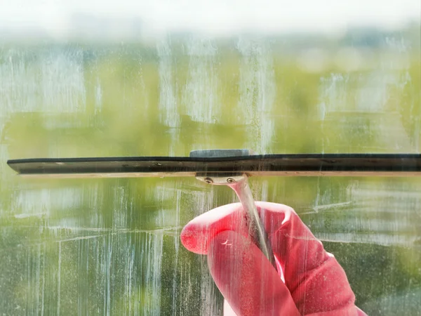 Hand in pink glove washes window glass by squeegee — Stock Photo, Image