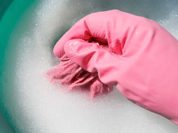 Hand in pink rubber glove rinsing wet cloth — Stock Photo, Image