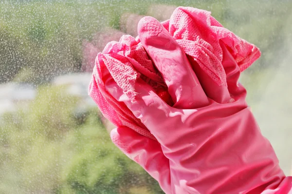 Mão em luva rosa lavagem janela de vidro — Fotografia de Stock