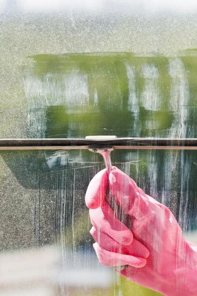 Hand in pink glove washes window pane by squeegee — Stock Photo, Image