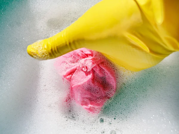 Hand in yellow rubber glove wrings out wet cloth — Stock Photo, Image