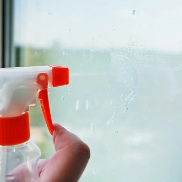 Liquid jet from spray bottle on window glass — Stock Photo, Image