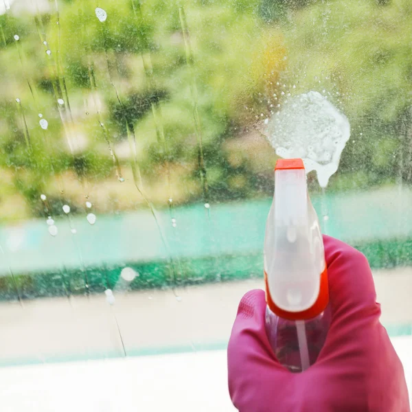 Liquid jet from spray bottle on glass window — Stock Photo, Image