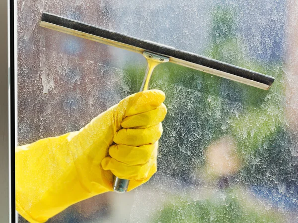 Hand in gelbem Handschuh wäscht Fenster mit Rakel — Stockfoto