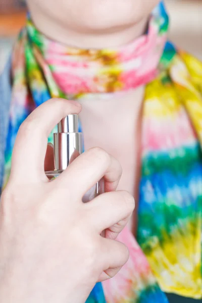 Woman sprays perfume on silk scarf from atomizer — Stock Photo, Image