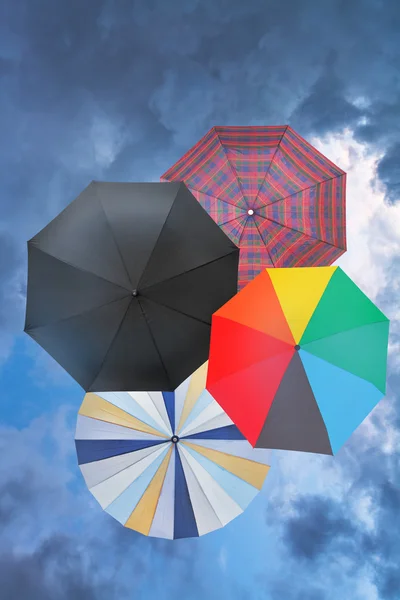 Four open umbrellas with blue rainy clouds — Stock Photo, Image