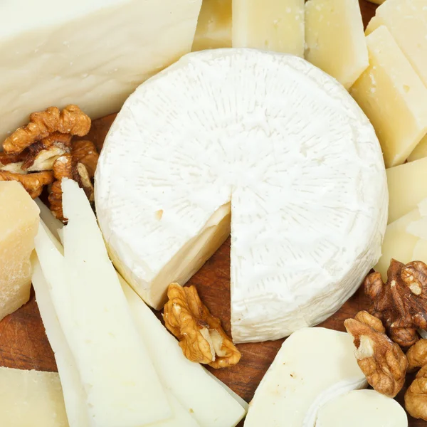 Assorted cheeses on wooden plate — Stock Photo, Image