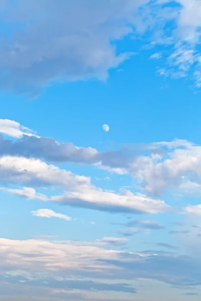 Moon and white clouds in blue evening sky — Stock Photo, Image