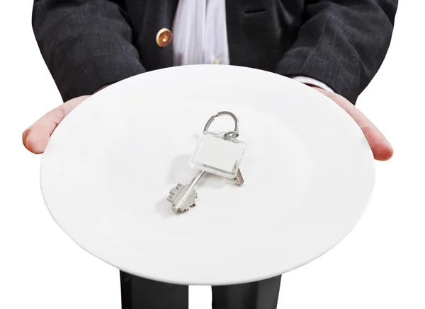 Бізнесмен тримає білу тарілку з новими дверними ключами — стокове фото