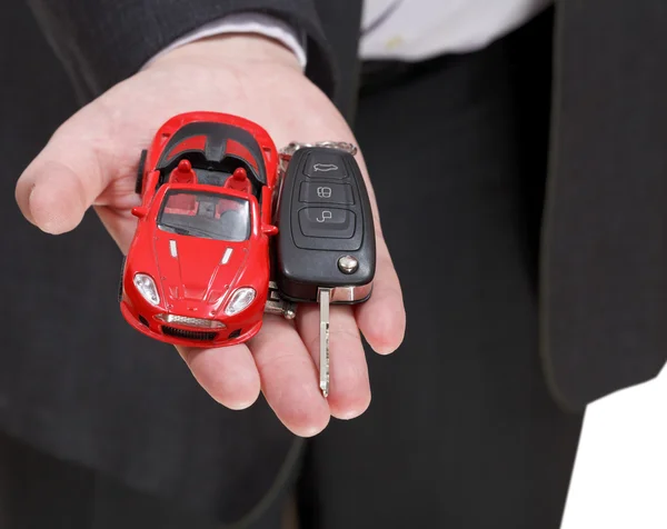 Carro vermelho e chave na mão do vendedor — Fotografia de Stock