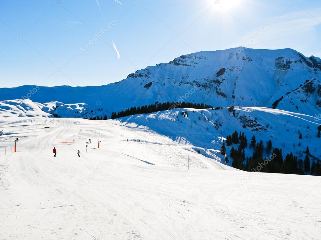 Ski run on snow slopes of mountains in sunny day
