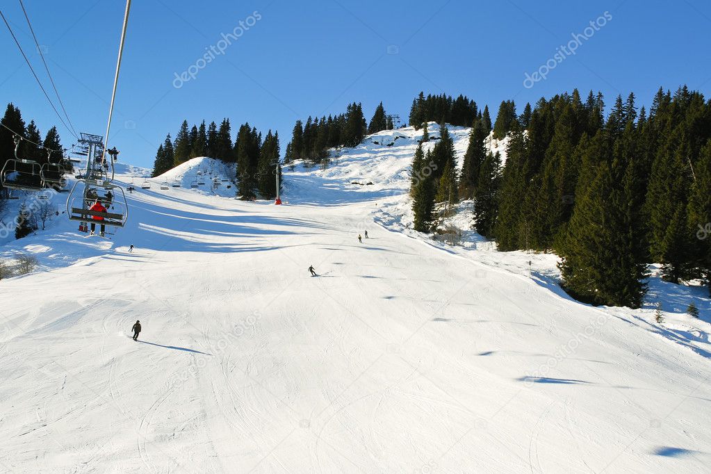 Ski lift and skiing tracks on snow Alps mountains