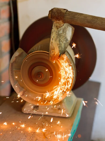 Sharpening garden hoer using a grinding machine — Stock Photo, Image