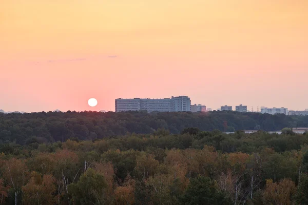 Słońce w czerwony wschód słońca nad domami i park miejski — Zdjęcie stockowe