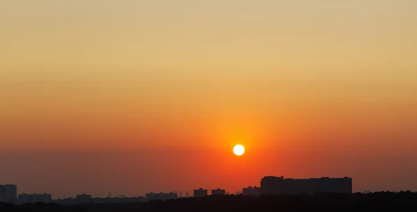 Sol no céu vermelho sobre a cidade ao nascer do sol — Fotografia de Stock