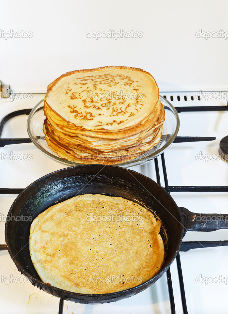 pancake in pan and stack of prepared pancakes
