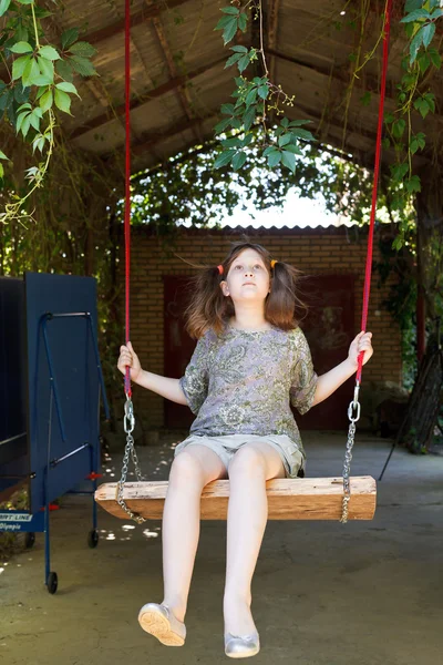 Flicka på swing i gården — Stockfoto
