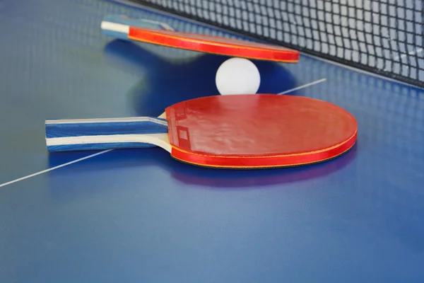 Dois remo, bola de tênis na mesa de ping pong azul — Fotografia de Stock