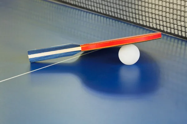 Paddle, tennis ball on blue ping pong table — Stock Photo, Image