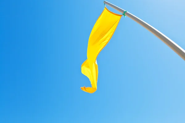 Beach safety yellow flag with blue sky — Stock Photo, Image