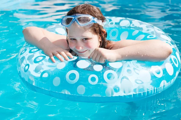 Fille sur le cercle gonflable dans la piscine en plein air bleue — Photo