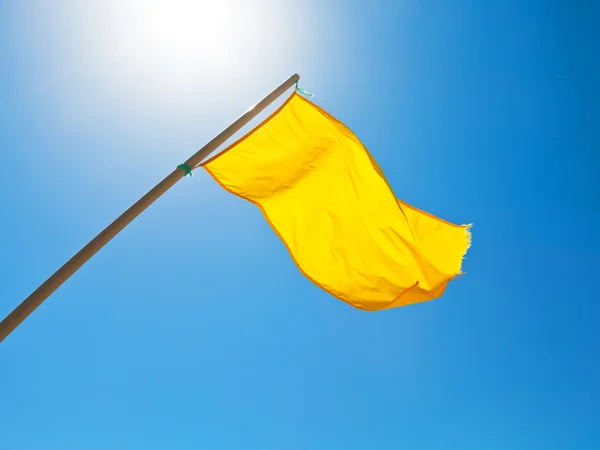 警告黄色旗帜在阳光下蓝蓝的天空下 — 图库照片