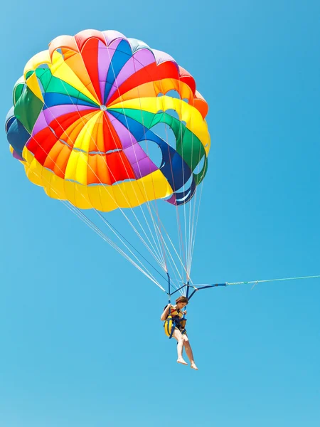 Menina parascendendo em paraquedas no céu azul — Fotografia de Stock