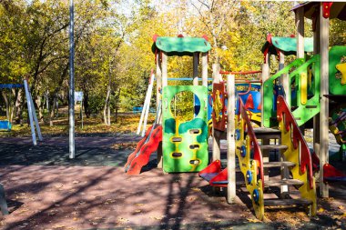 Güneşli bir sonbahar gününde şehir parkında renkli ahşap slaytlar ve oyun parklarında evler