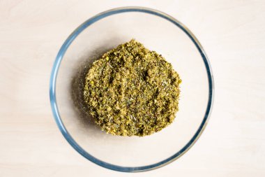 Kırık şifalı bitkilerin ve açık kahverengi masada cam kasedeki bitkilerin kuru görüntüsü.