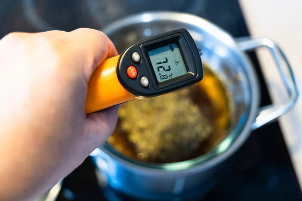 家庭厨房陶瓷炉上红外温度计测定水浴中药草的煮沸温度 — 图库照片