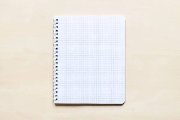薄茶色の板に渦巻状のノートの正方形の紙の上面図 — ストック写真