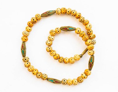 Beyaz kağıda işlenmiş kemik ve işlemeli pirinç boncuklardan yapılmış klasik bir kolye.