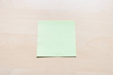 Açık kahverengi tahta üzerinde boş yeşil kağıt sayfa üst görünümü