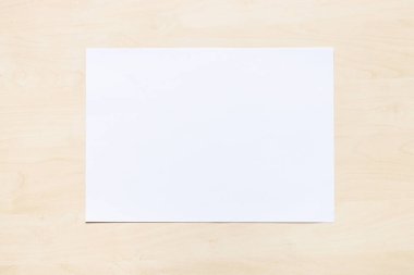 Açık kahverengi tahta üzerinde beyaz ofis kağıdının üst görüntüsü