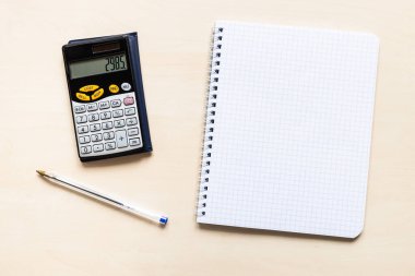 Açık kahverengi ahşap tahta üzerinde boş sayfanın kare kağıt üst görünümü spiral defter, kalem ve finansal hesap makinesi