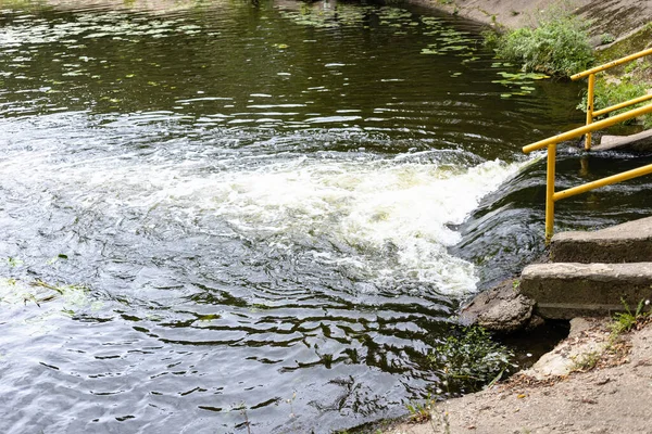discharge of water from underground river into city pond