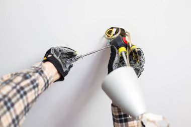 Elektrikçi evdeki tavan lambasının elektrik bağlantısını tamir ediyor