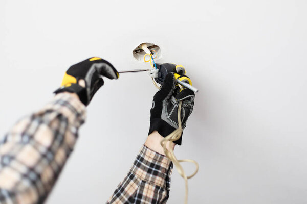 electrician repairing electrical wiring of ceiling lamp at home