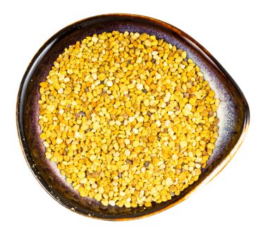 Beyaz arka planda doğal arı poleni olan seramik kasenin üst görüntüsü