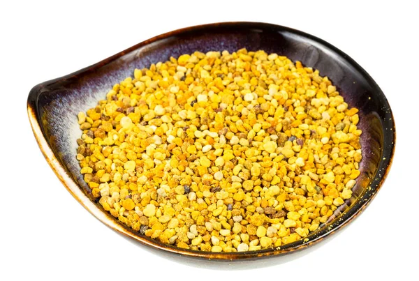 Beyaz zemin üzerinde doğal arı poleni bulunan seramik kase