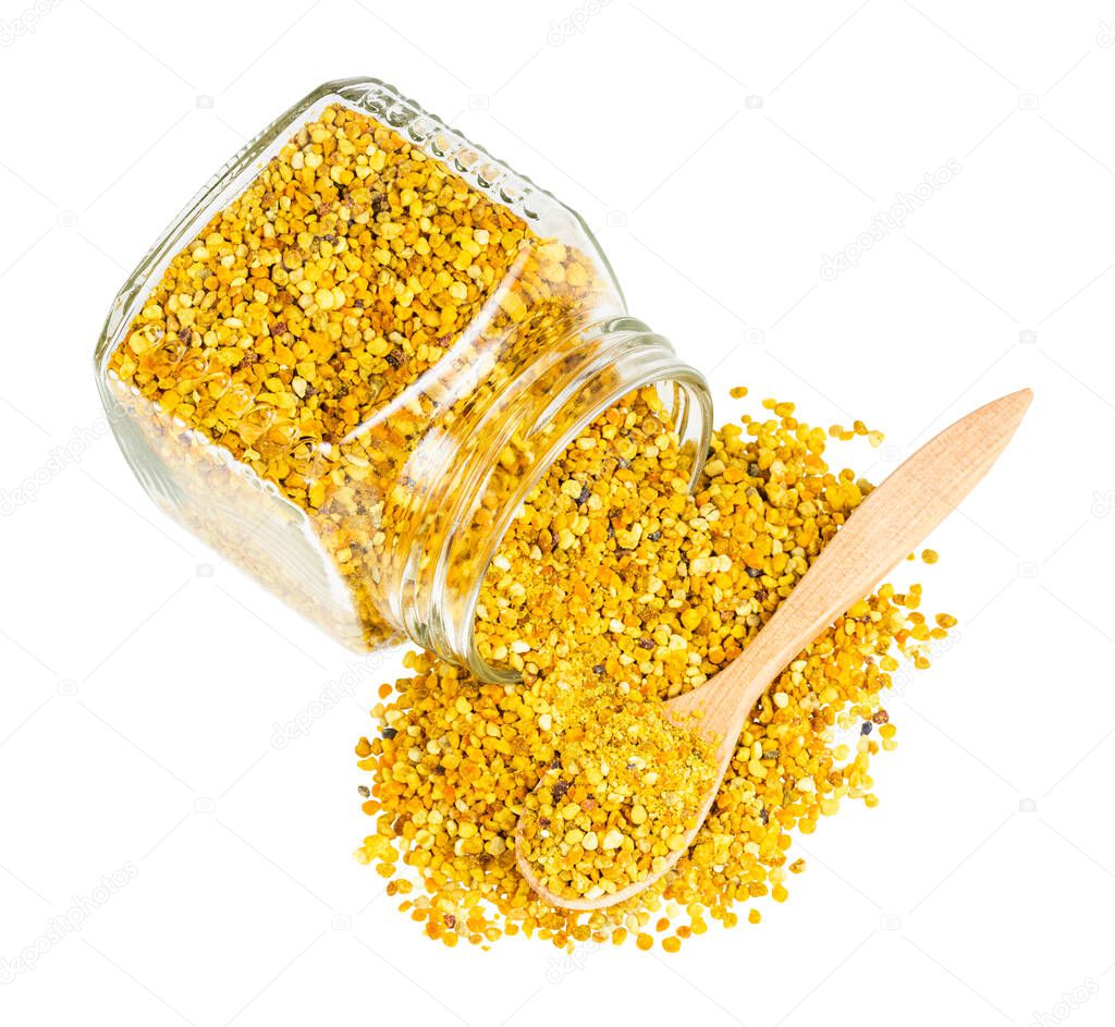 top view of wooden spoon in pile of bee pollen spilled from overturned glass jar isolated on white background