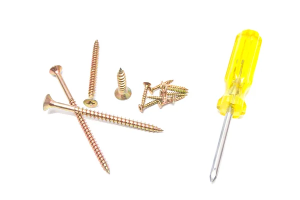 Many golden screws and yellow screwdriver — Stock Photo, Image