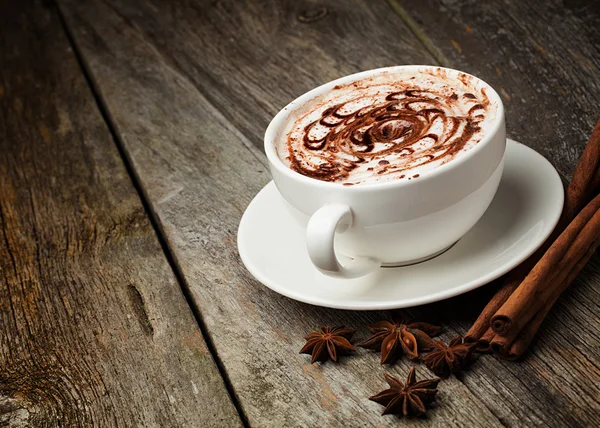 Koffiekop en bonen, kaneelstokjes, noten en chocolade op woo — Stockfoto