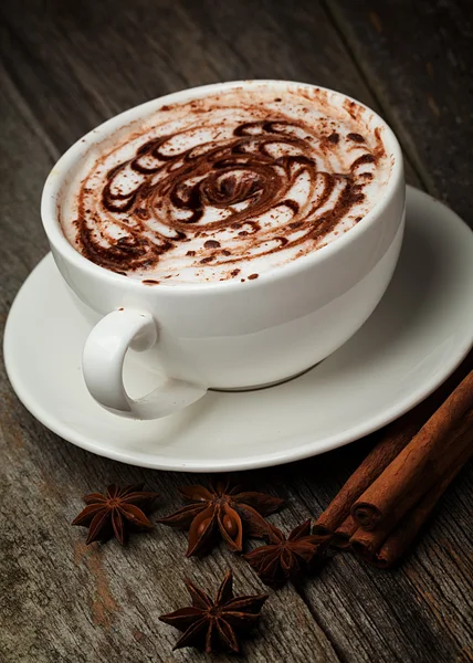 Coffee cup and beans, cinnamon sticks, nuts and chocolate on woo Stock Photo
