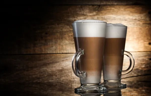 Geurende koffie latte in glazen bekers op houten achtergrond — Stockfoto