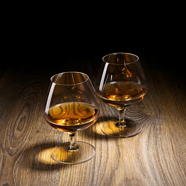 Dva pohárů brandy vyhřívané záře světel na dřevěné — Stock fotografie