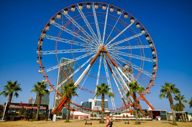 Big red and white ferris wheel on the seafront in Batumi, Georgia.Ali and Nino Monument in Front and ABC Tower in the Background.