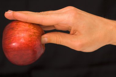 Bir elma koyu arka plan üzerinde tutan adamın el
