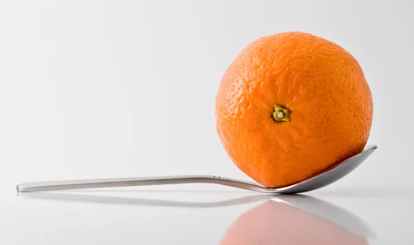 Metal tea-spoon with tangerine in it — Stock Photo, Image